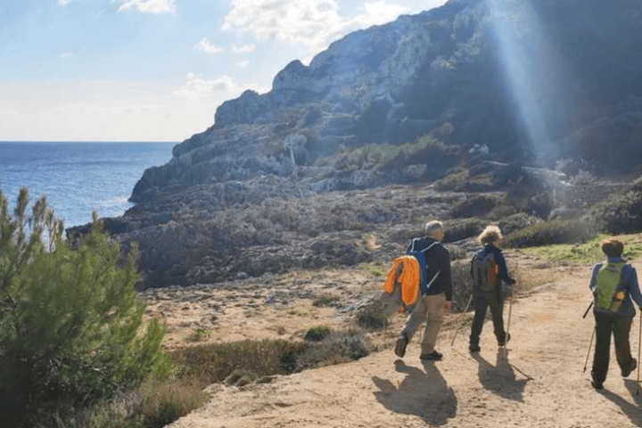 a group of people walking on a beach with a mountain in the background