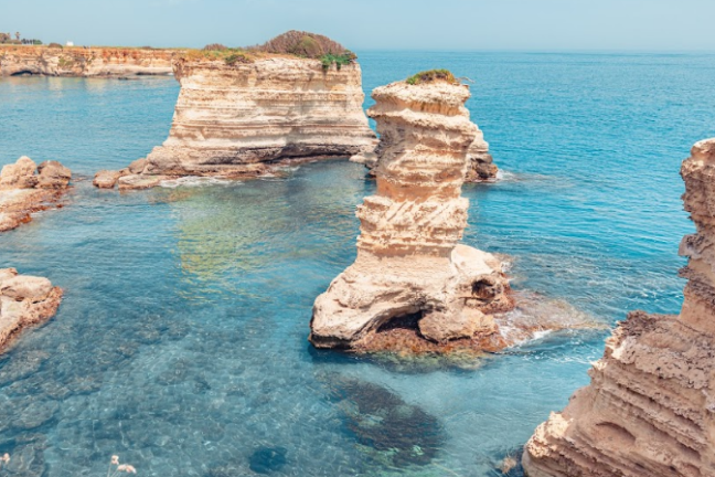 a group of people sitting on a rock near the ocean