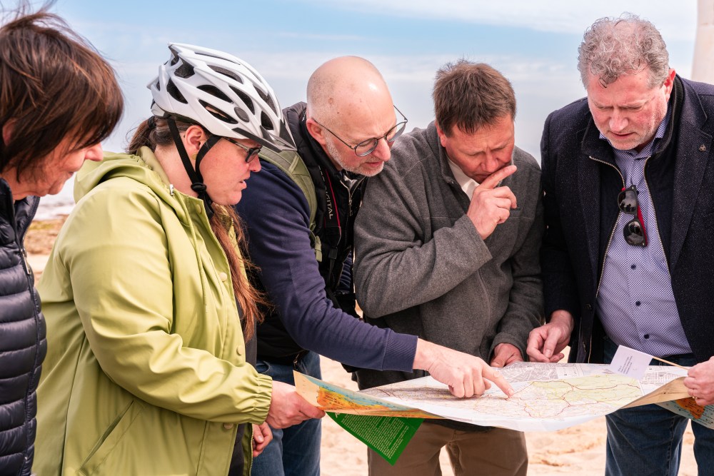 Group of people examining a map outdoors.